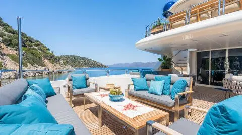 Amadea yacht deck at sunset with blue cushions and lounge chairs