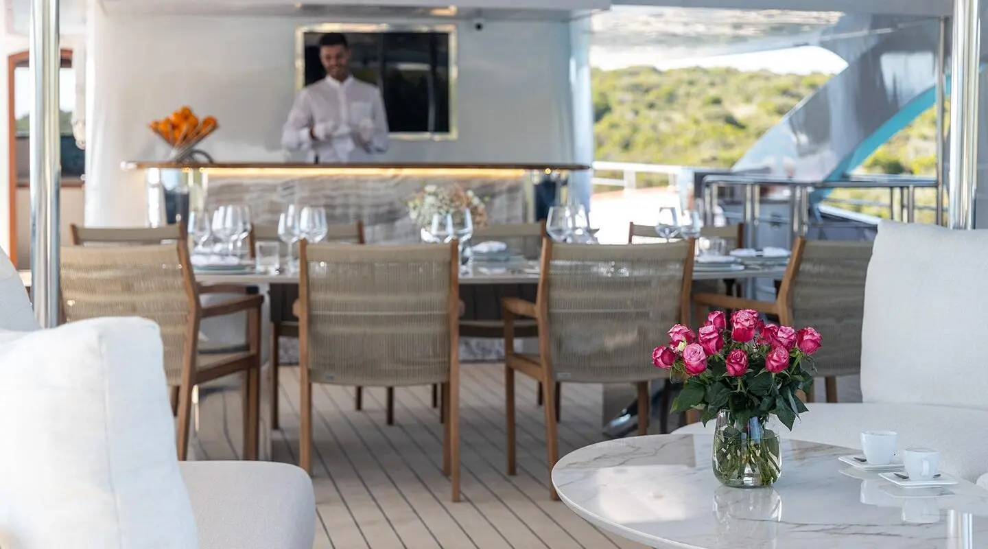 Olimp luxury yacht charter deck at sunset with seating and flowering table