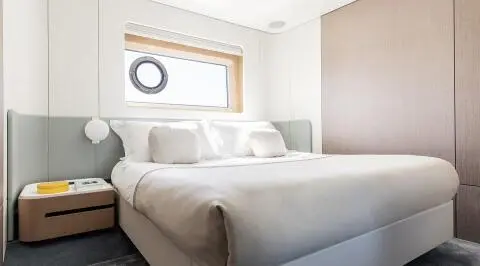 Viva II motor yacht cabin with two large beds, neutral decor, window view