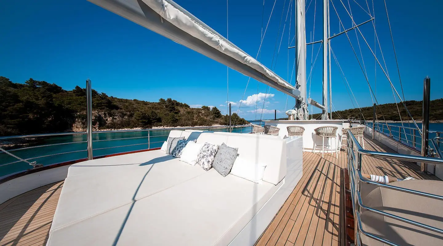 Nocturno yacht sundeck with white seating, railing, and blue sea backdrop