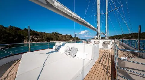 Nocturno yacht sundeck with white seating, railing, and blue sea backdrop