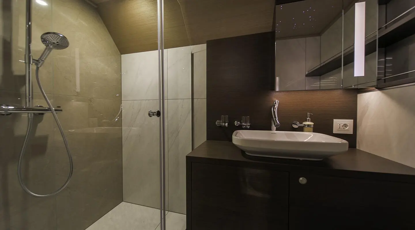 Omnia yacht bathroom interior with glass shower, white basin, and dark wood vanity