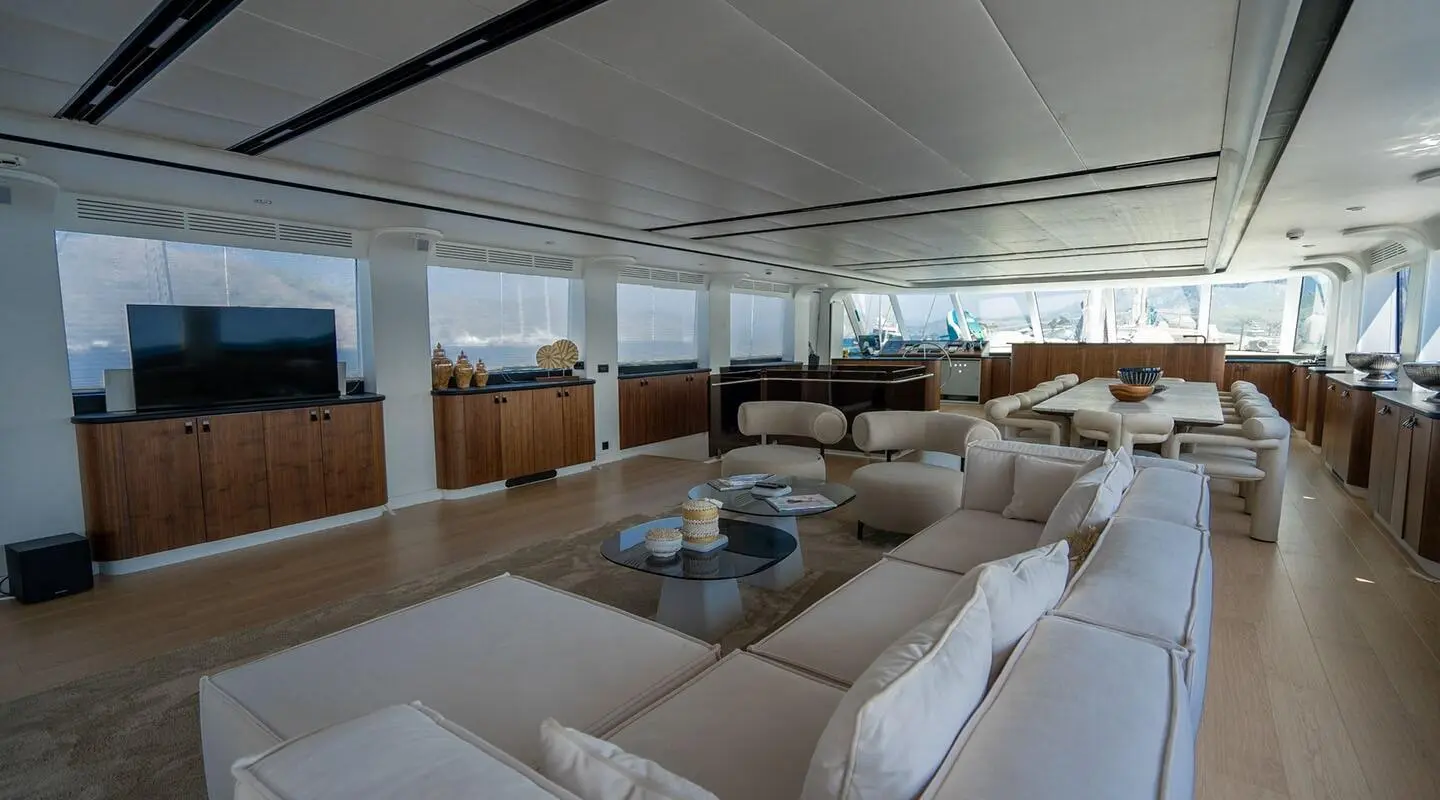 Sunlit yacht De Love interior with white cushioned seating and glass windows