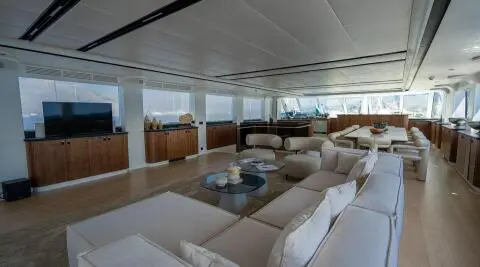 Sunlit yacht De Love interior with white cushioned seating and glass windows