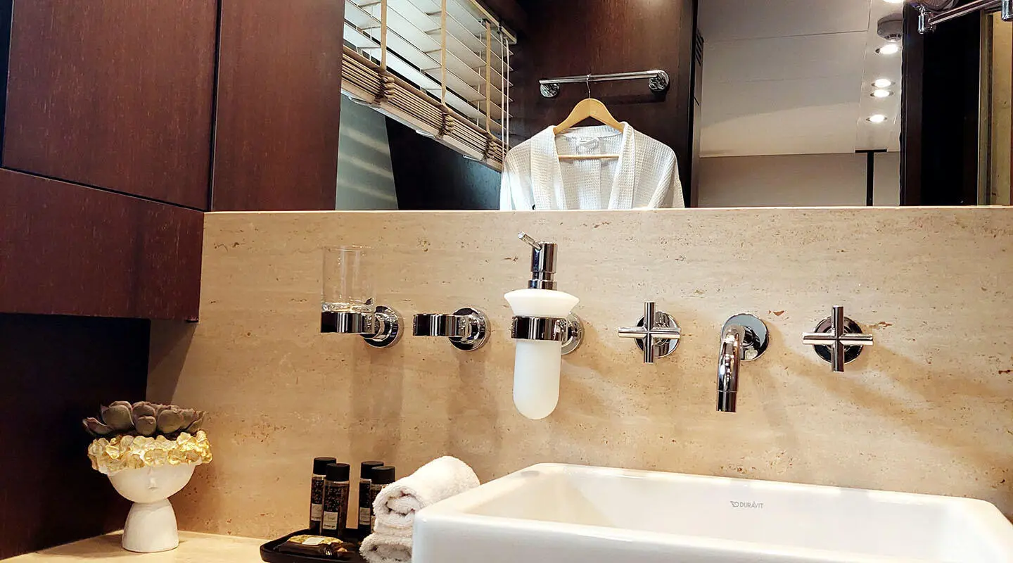 Miraval yacht bathroom with tiled wall, faucets, and a white sink.