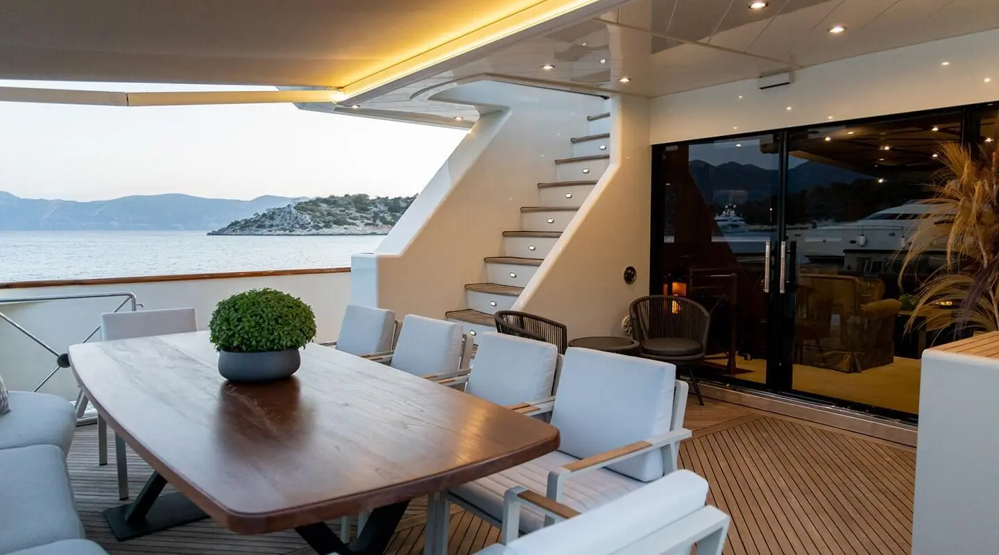 Aquila motoryacht aft deck with table, chairs, stairs, and horizon view