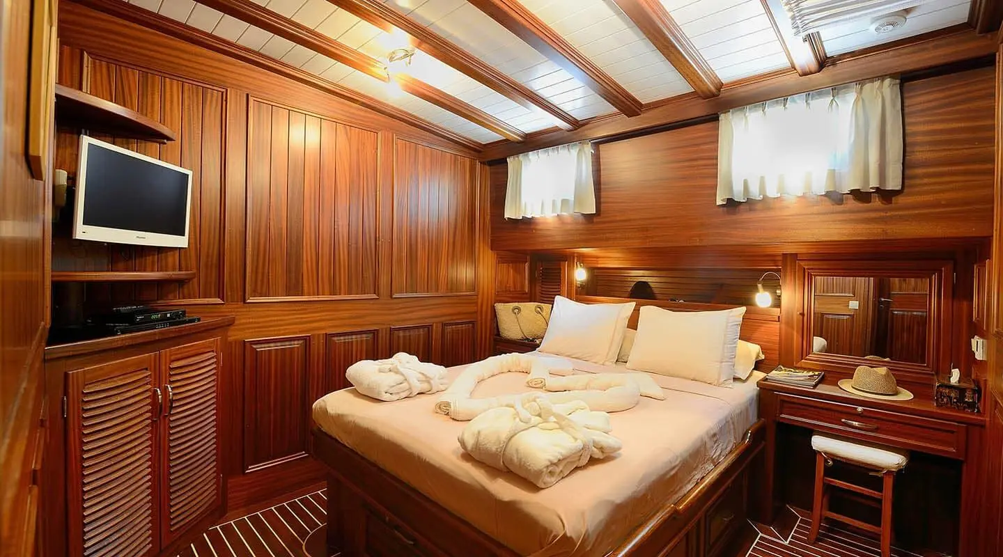Zephyria II yacht interior: warm wooden panels, bed with pillows, soft lighting
