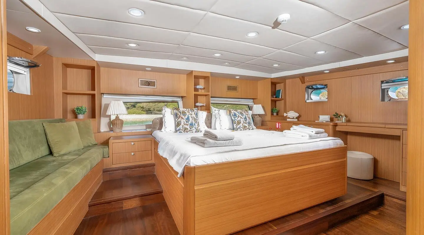 Interior view of a gulet Artemis master cabin with wooden cabinetry and bed.