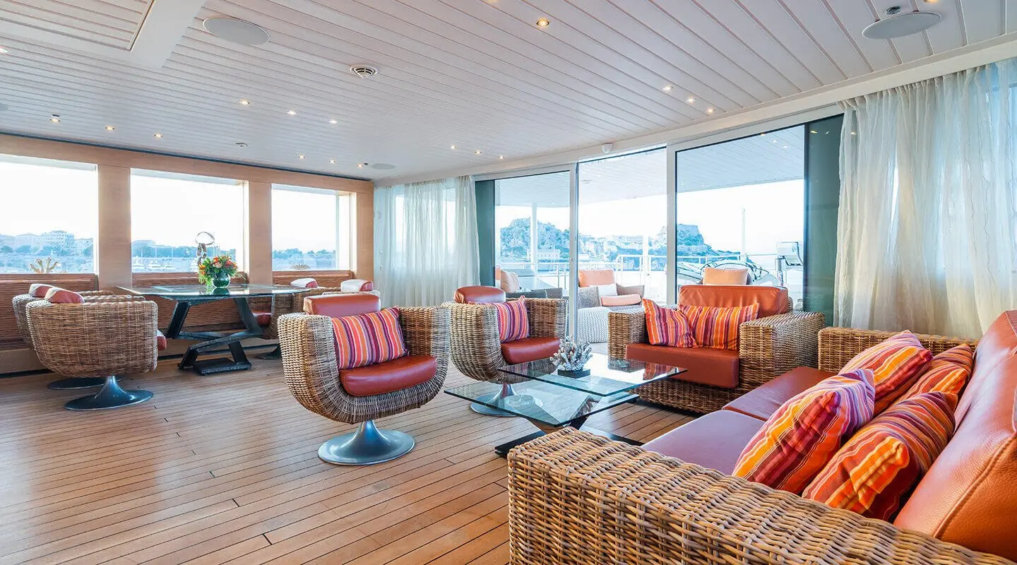 Luxurious yacht Serenity interior with wicker chairs, colorful cushions, and large windows