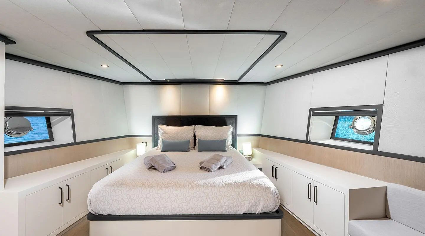 Calm Down yacht bedroom: large bed with headboard, white linens, cabinets, soft lighting