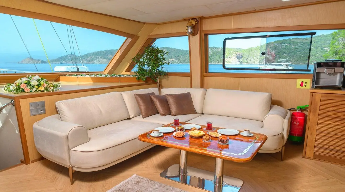 Luxurious yacht Belgin Sultan interior with beige seating and teak table at sunset