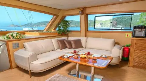 Luxurious yacht Belgin Sultan interior with beige seating and teak table at sunset