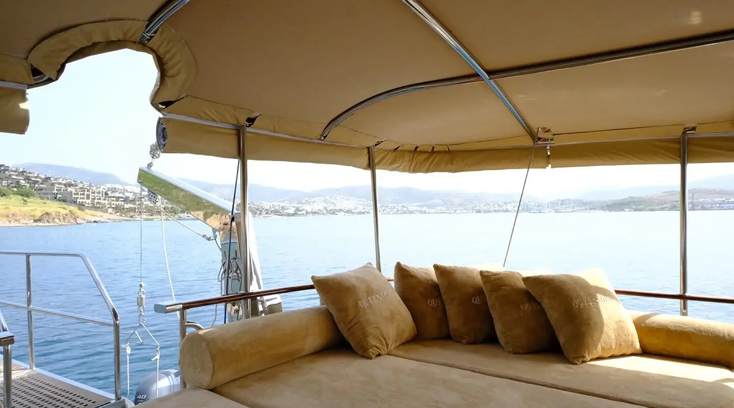 Queen Of Sea yacht lounging area with cushioned seating under beige canopy, sea view