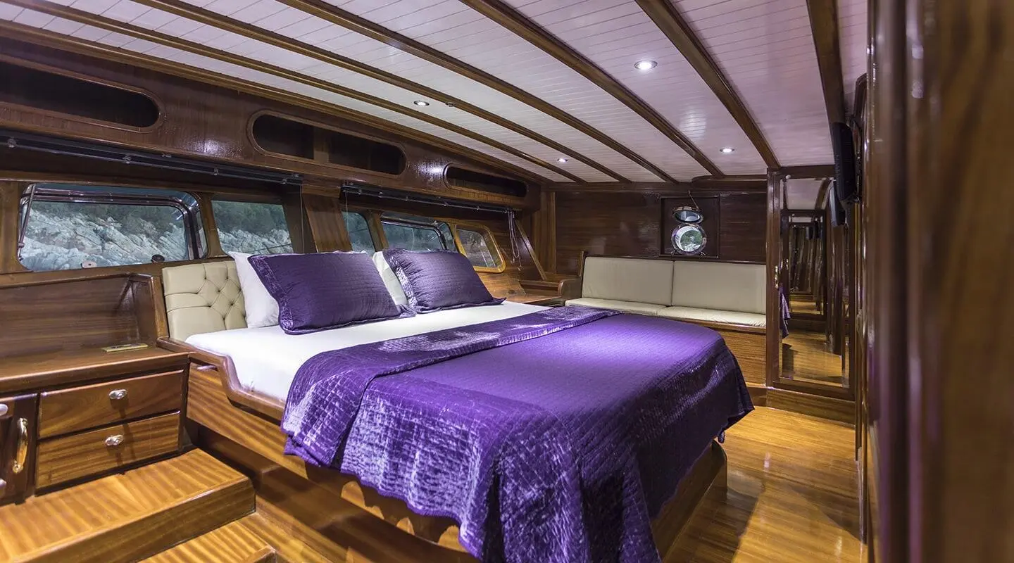 Grace 1 yacht interior: luxurious cabin with purple bedspreads and wooden accents