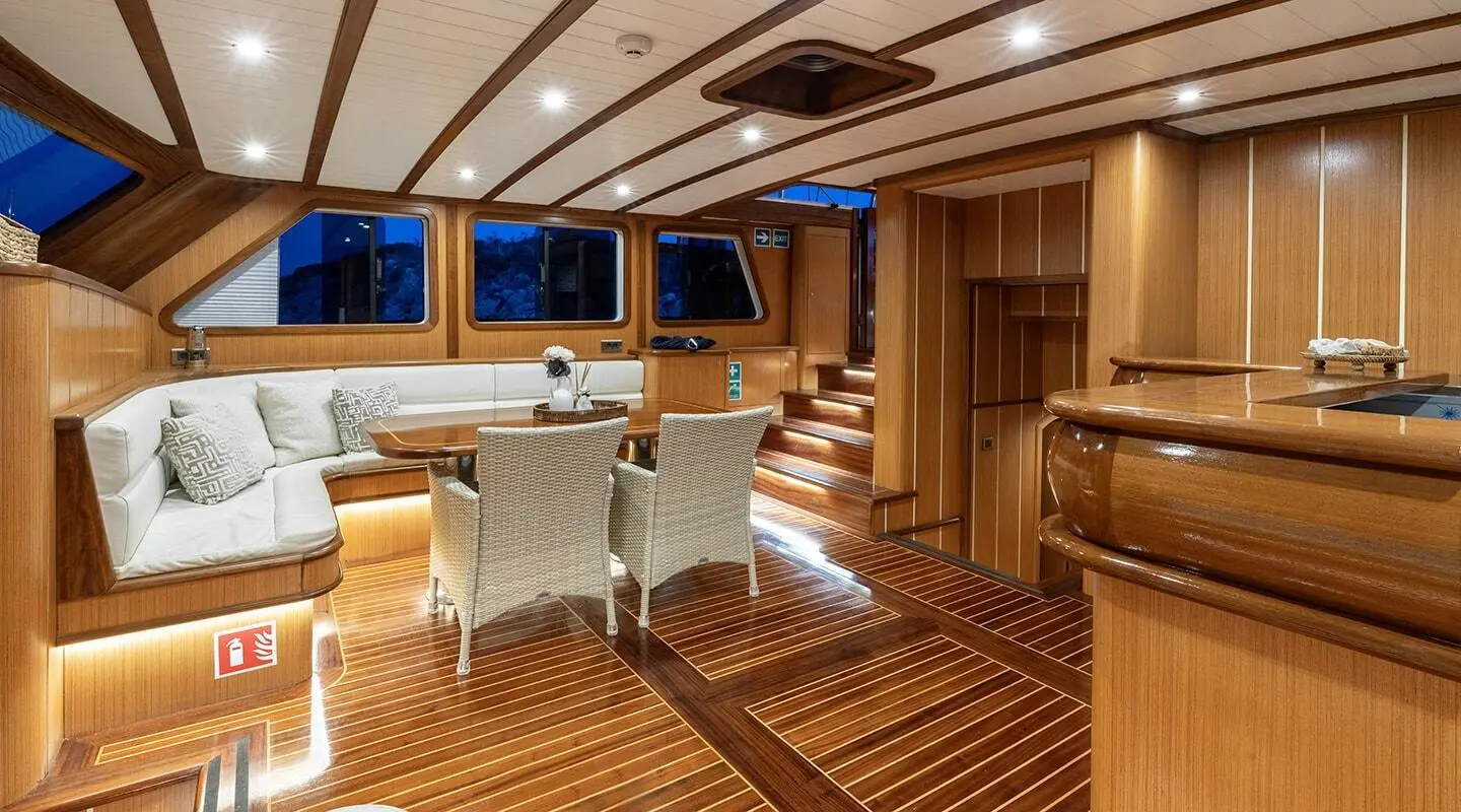 Gozdem The One yacht interior with wooden deck, dining table, and seating