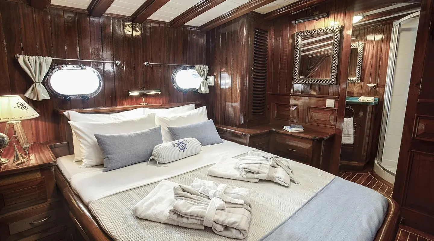 Wood-paneled cabin with a large bed and porthole windows