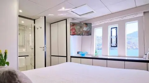 Genny yacht interior with double cabin, white bedding and blue accents