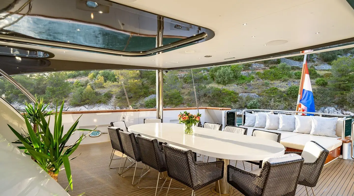Navilux yacht dining area under a covered deck with a long table set for guests
