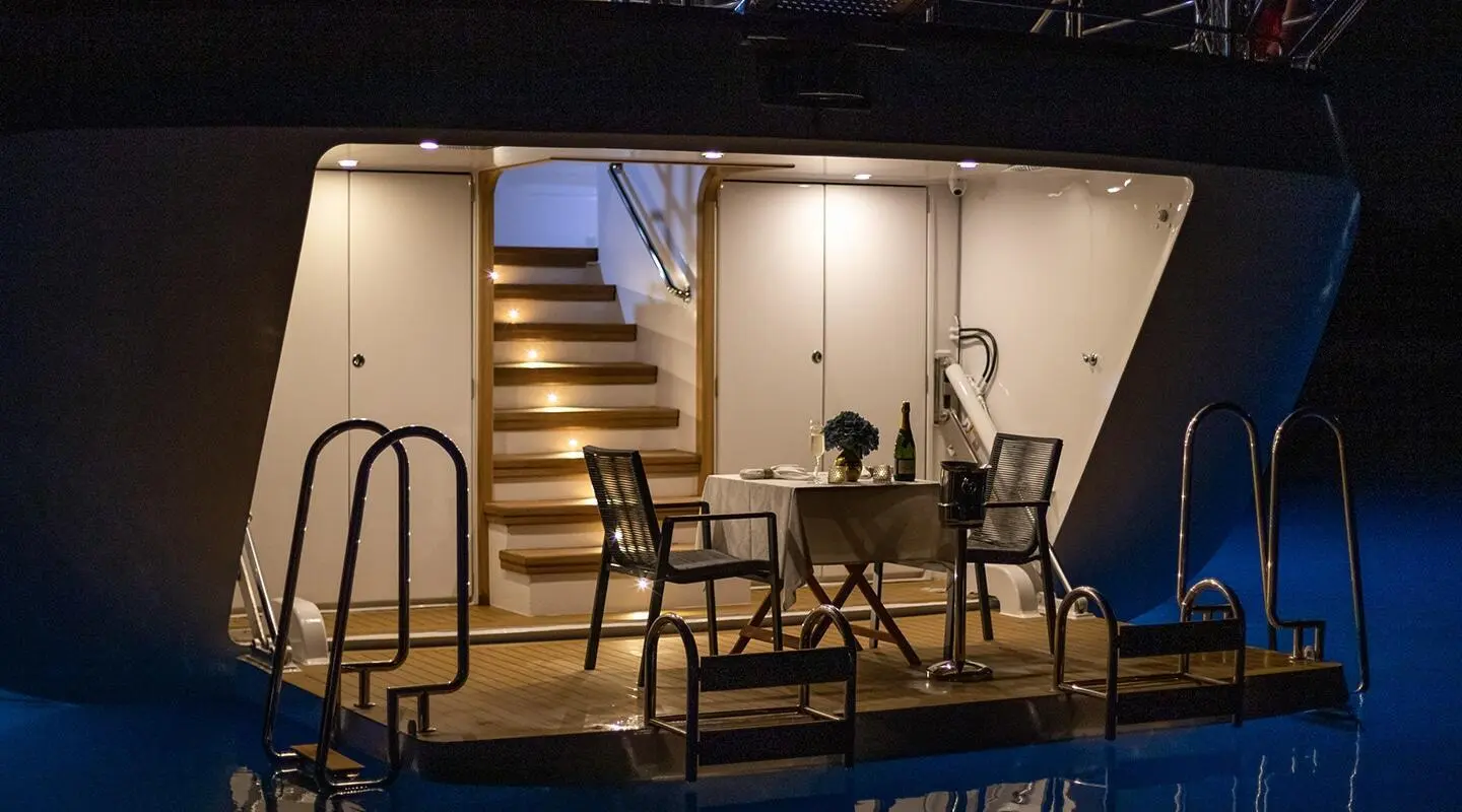 Love Story yacht deck dining area with table, chairs, stairs under cabin lighting