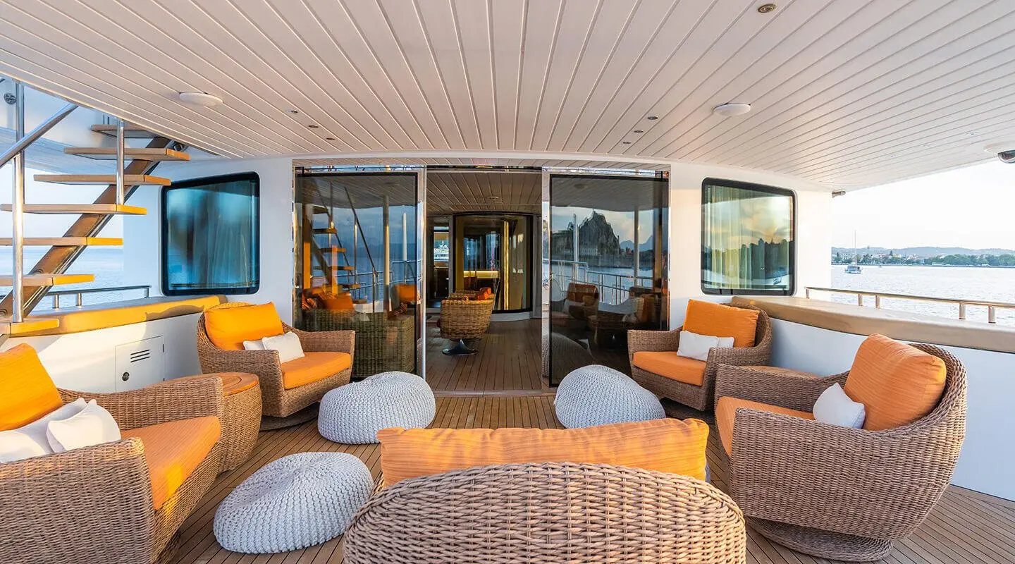 Serenity yacht deck seating area with orange cushions and glass doors