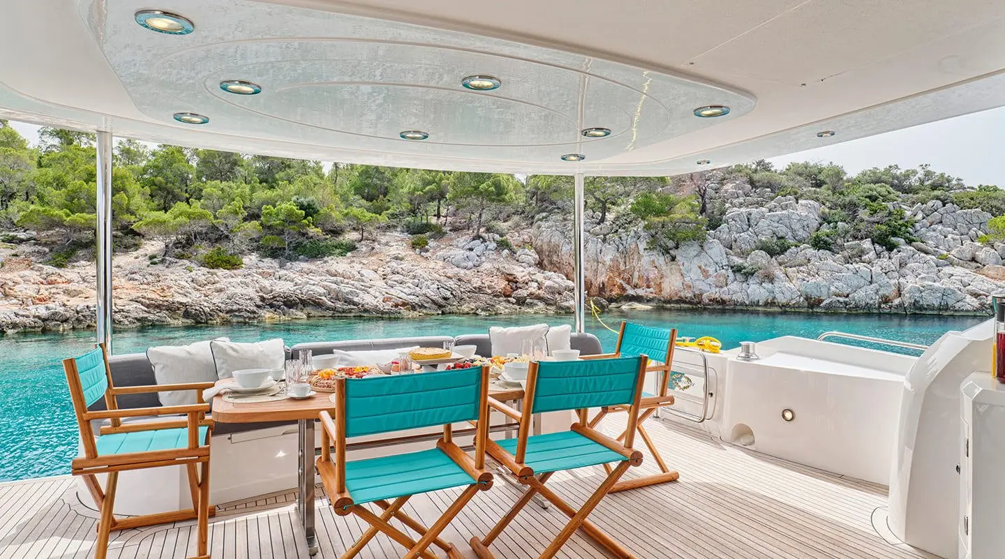 Yacht M Five dining deck with two turquoise chairs facing sunset sea view
