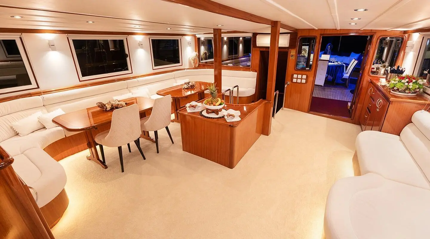 Aurum yacht interior with wooden cabinetry, seating, and a dining area at sunset