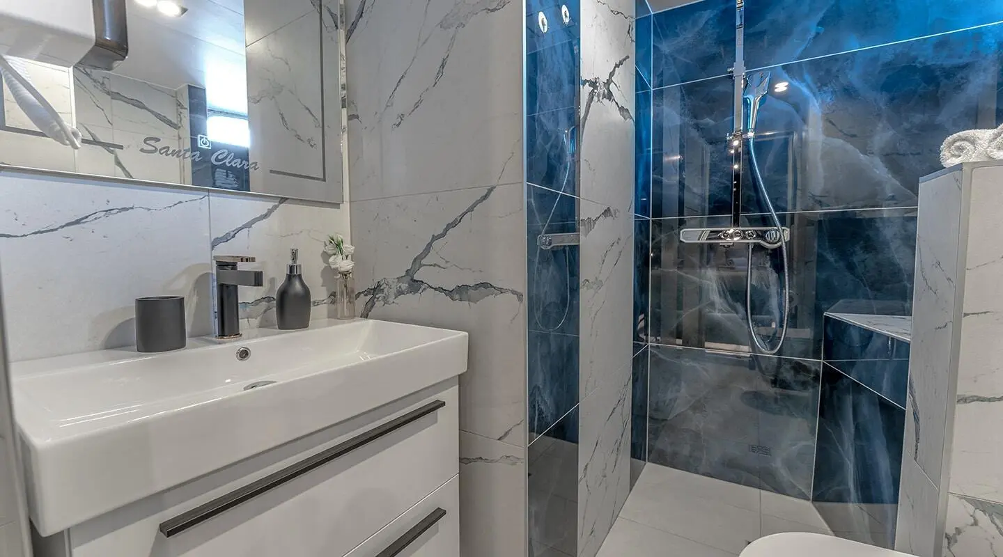 Bathroom onboard Santa Clara yacht with sink, mirror, and tiled shower