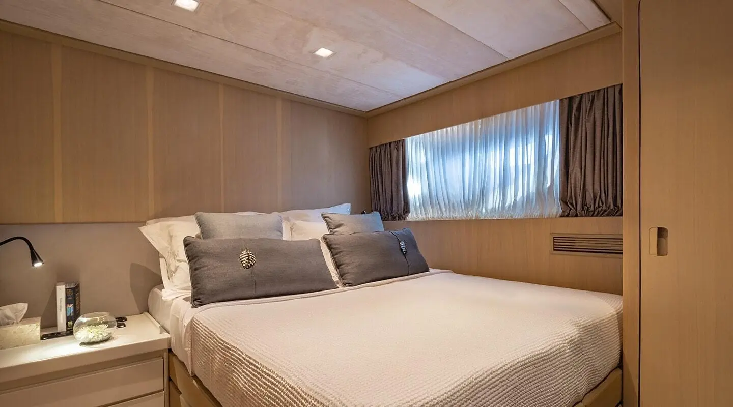 Interior of a luxury yacht cabin with bed, two pillows, wooden walls