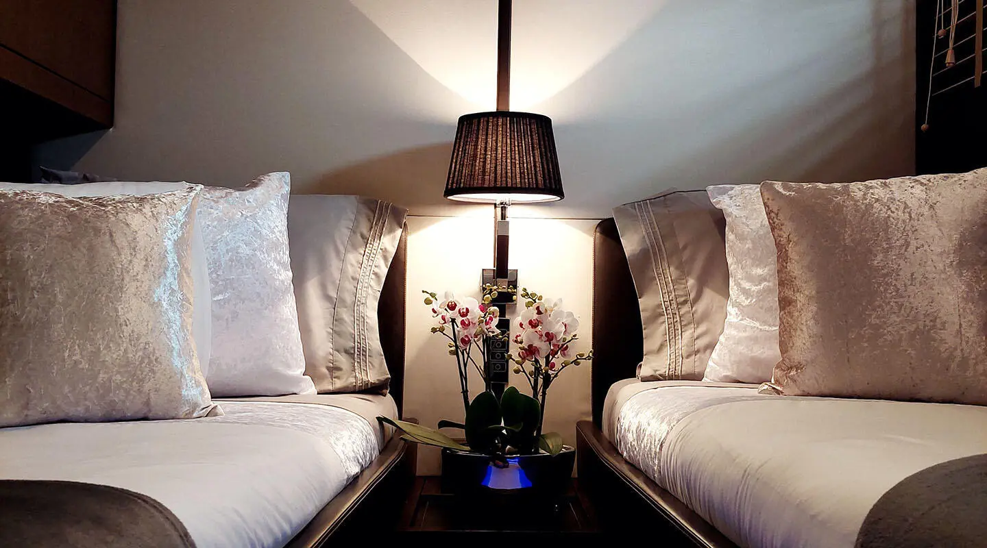 Miraval yacht twin cabin interior with two beds, lamps, and decorative pillows