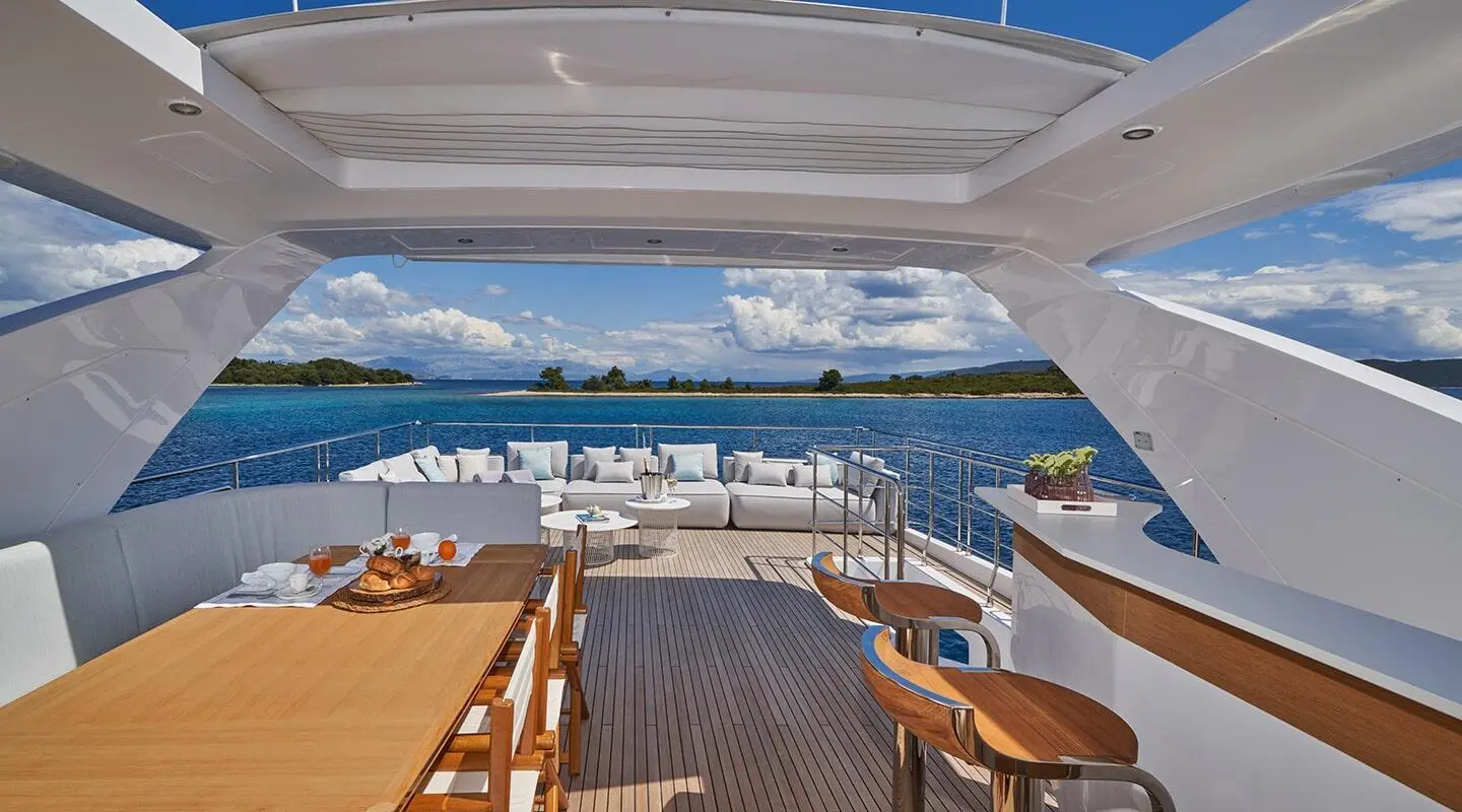 Deck aft of Aluminia Too yacht with seating, sun loungers, and marina viewed