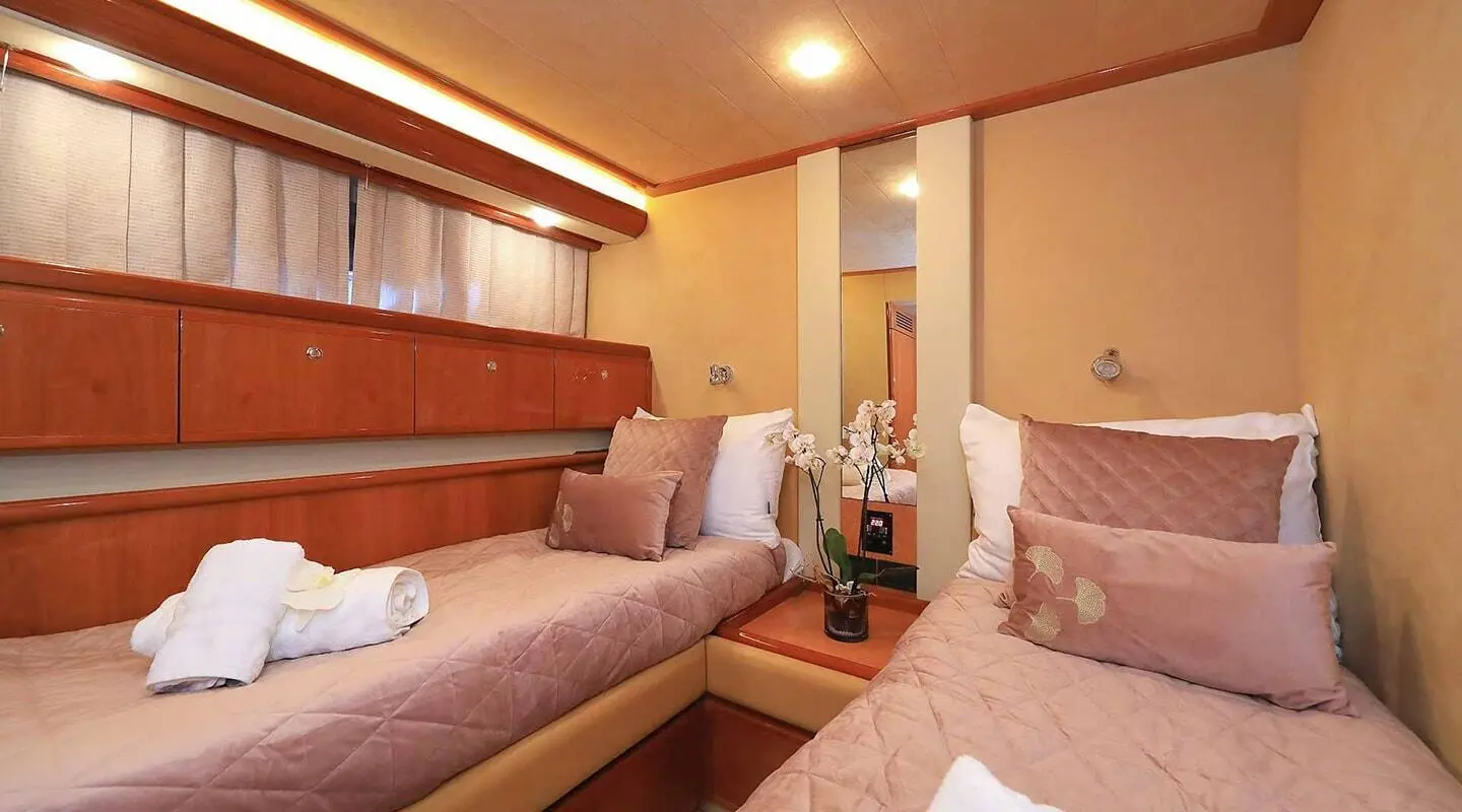 Interior of Quo Vadis I yacht with beige seating, wooden cabinets, and pillows