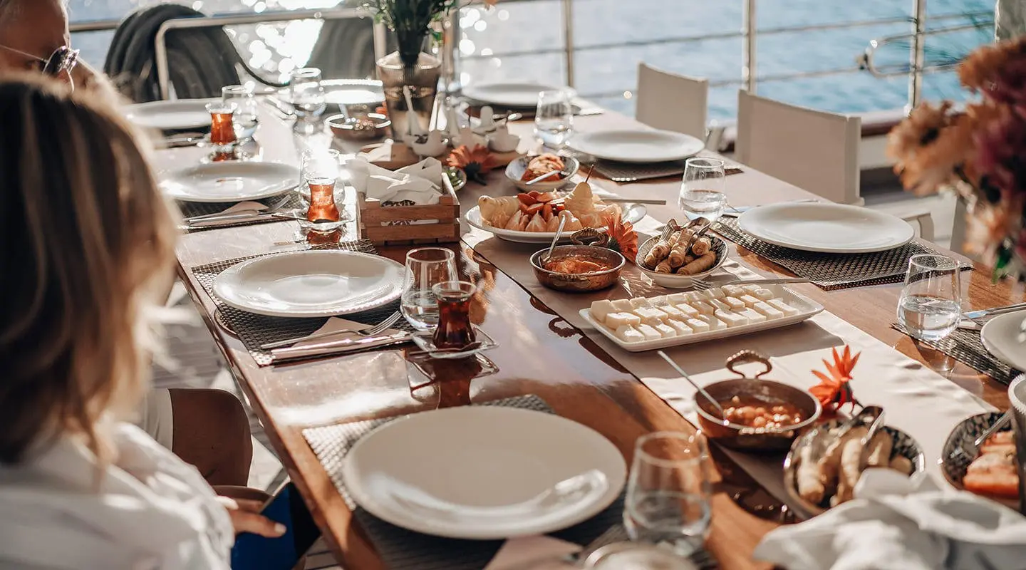 Queen Of Makri yacht at sunset with a long dining table set for guests