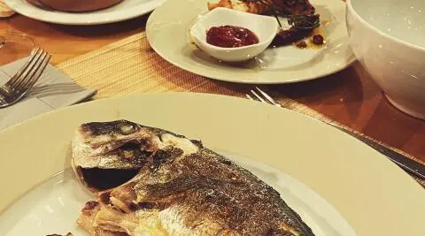 Silver Moon yacht dining scene with grilled fish on plate and sauces nearby