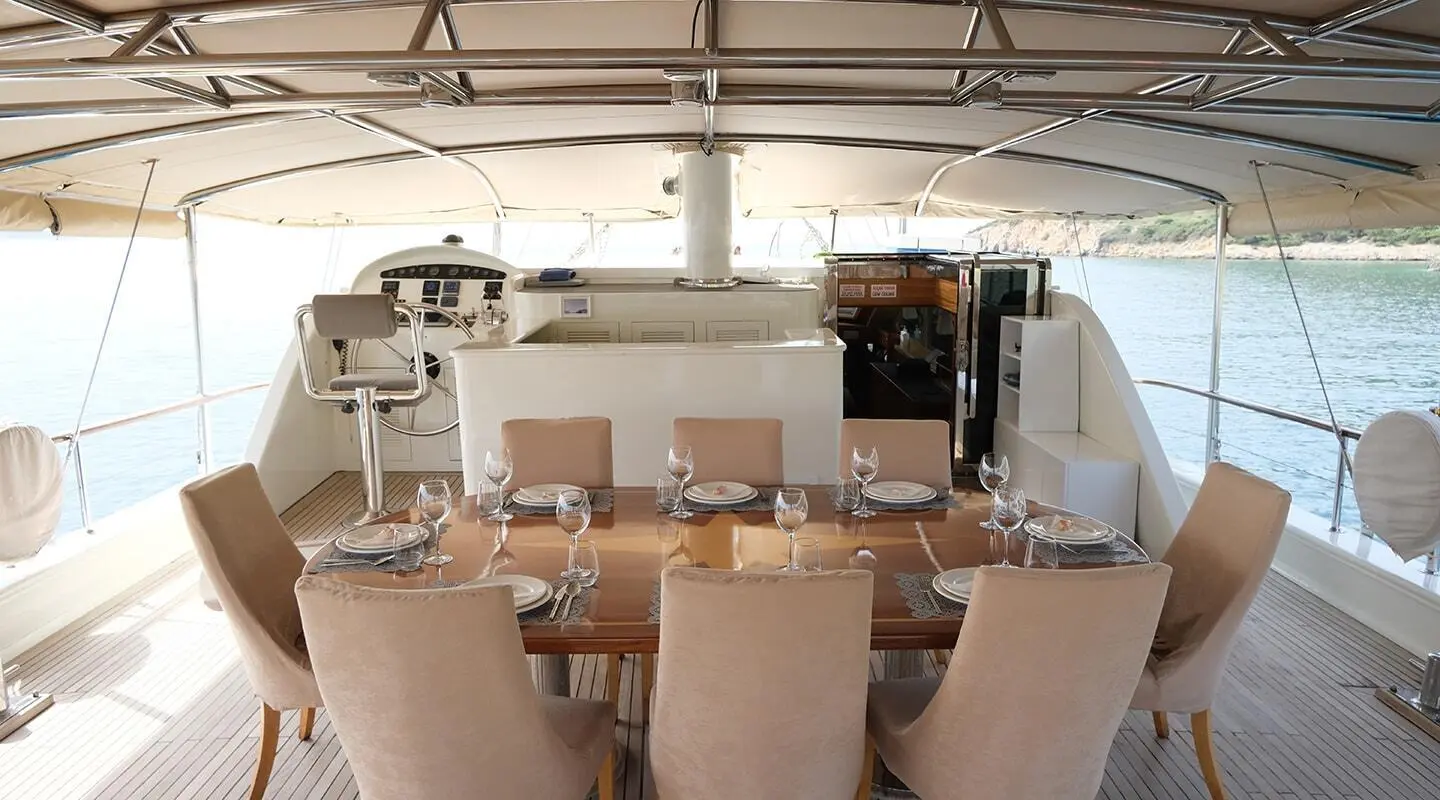 Queen Of Sea yacht interior with dining area and sunlit wooden deck seating