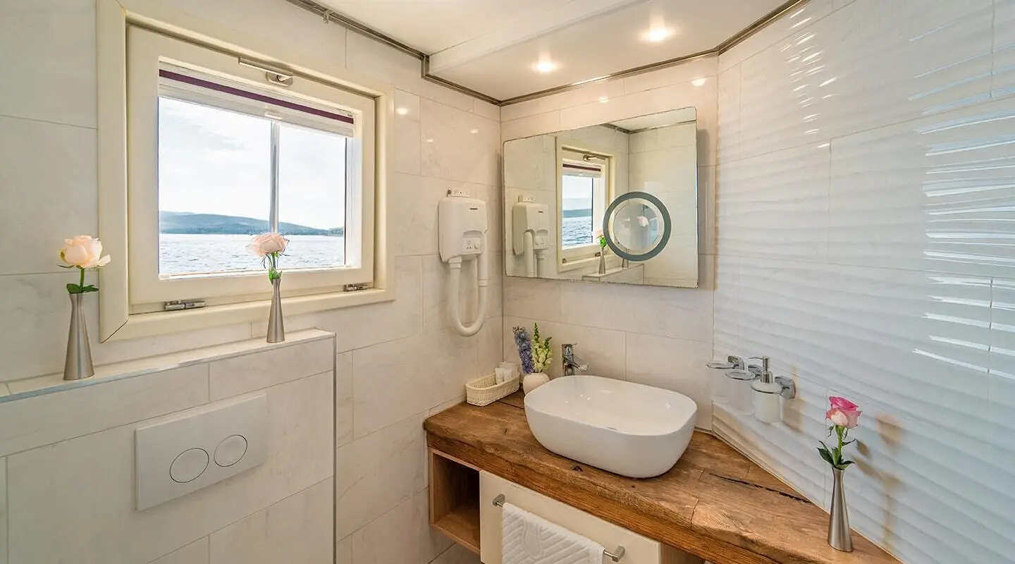 Luxurious Riva yacht interior with a wooden vanity, sink, mirror, and porthole window