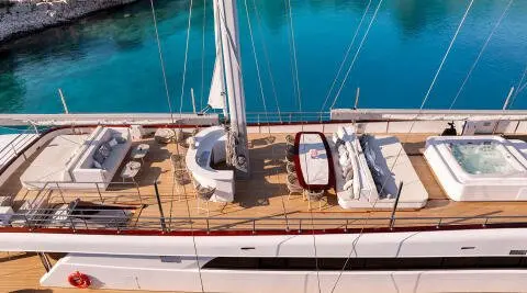 Top-down view of Nocturno yacht deck with seating, sun loungers, and railing by clear blue water