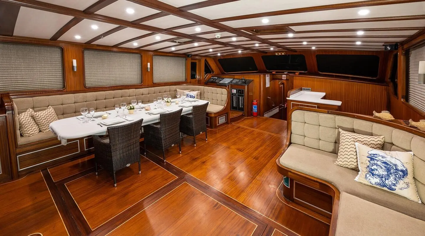 Interior with long dining table, seating, and wood paneling on the yacht