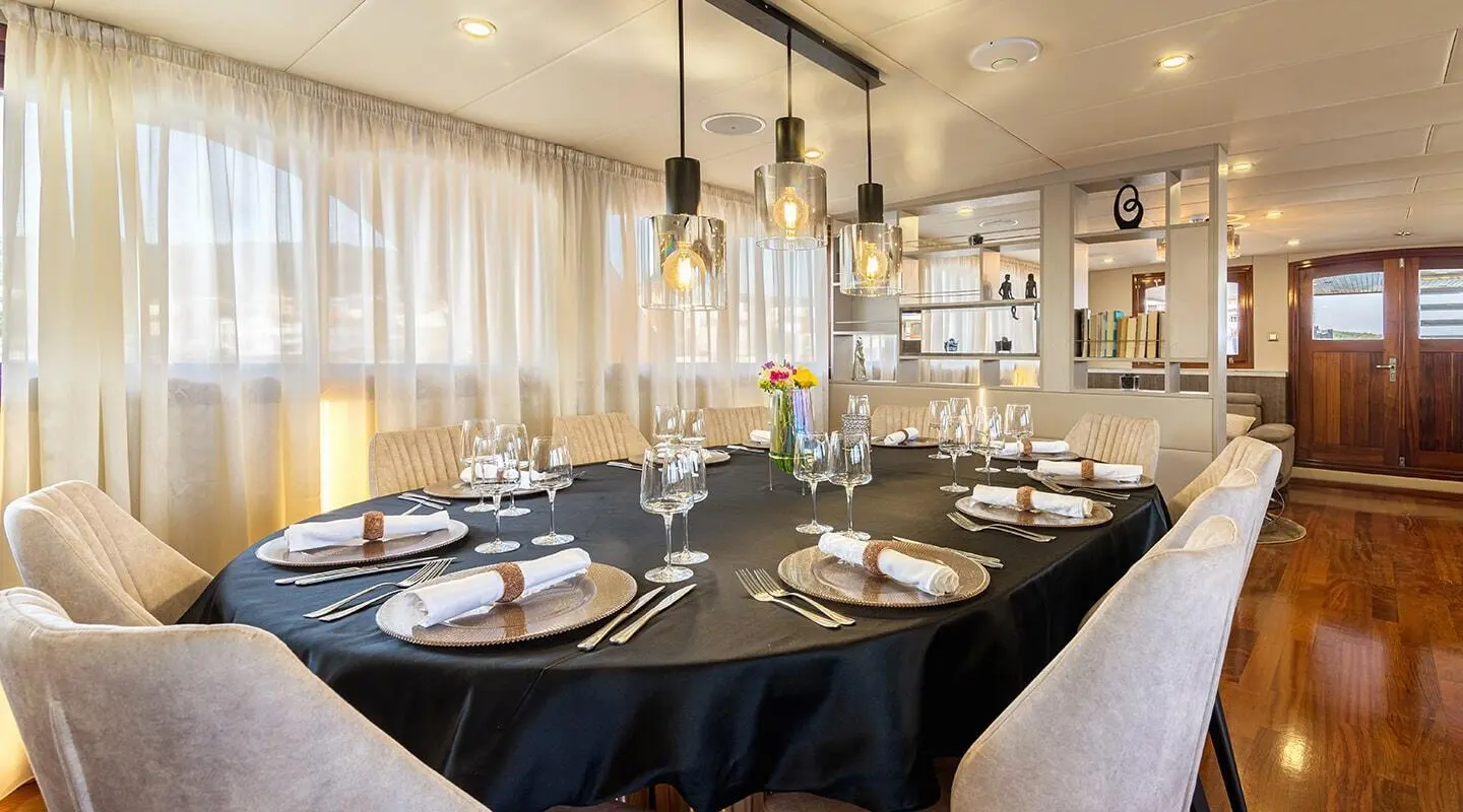 Round table set for dining on Melody yacht interior with flowers and place settings