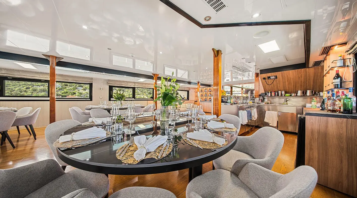 Karizma luxury yacht dining area interior at sunset with round table and white chairs