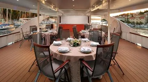 Queen Eleganza yacht dining area at sunset with table settings and chairs