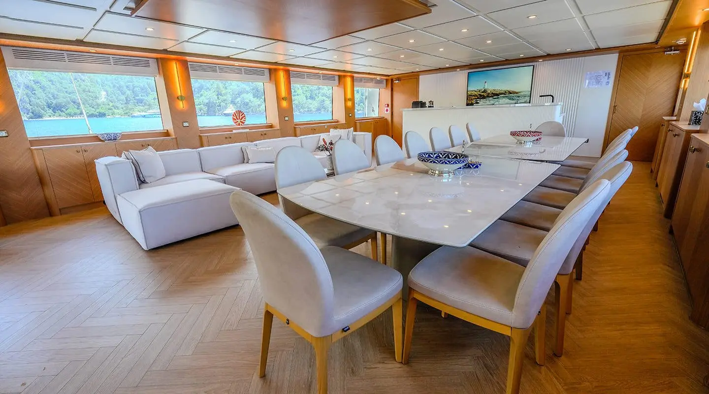 Luxurious yacht interior with a long white sofa and marble table in a bright lounge