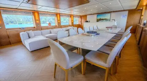 Luxurious yacht interior with a long white sofa and marble table in a bright lounge