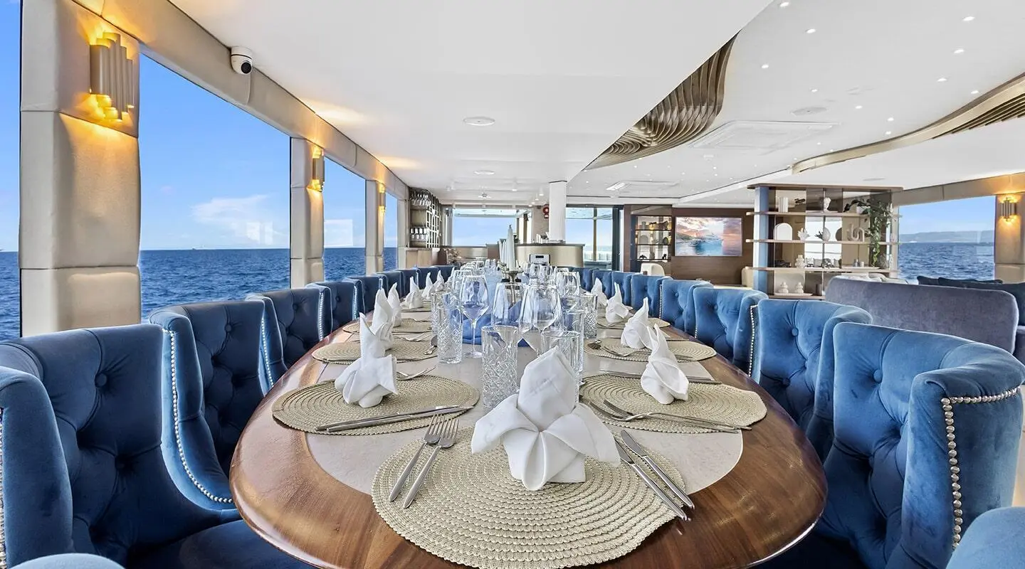 Bella yacht dining area aboard a luxury vessel with blue tufted seating and place settings