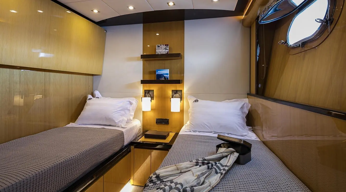 Interior of luxury yacht cabin with two beds, wood paneling, and built-in storage