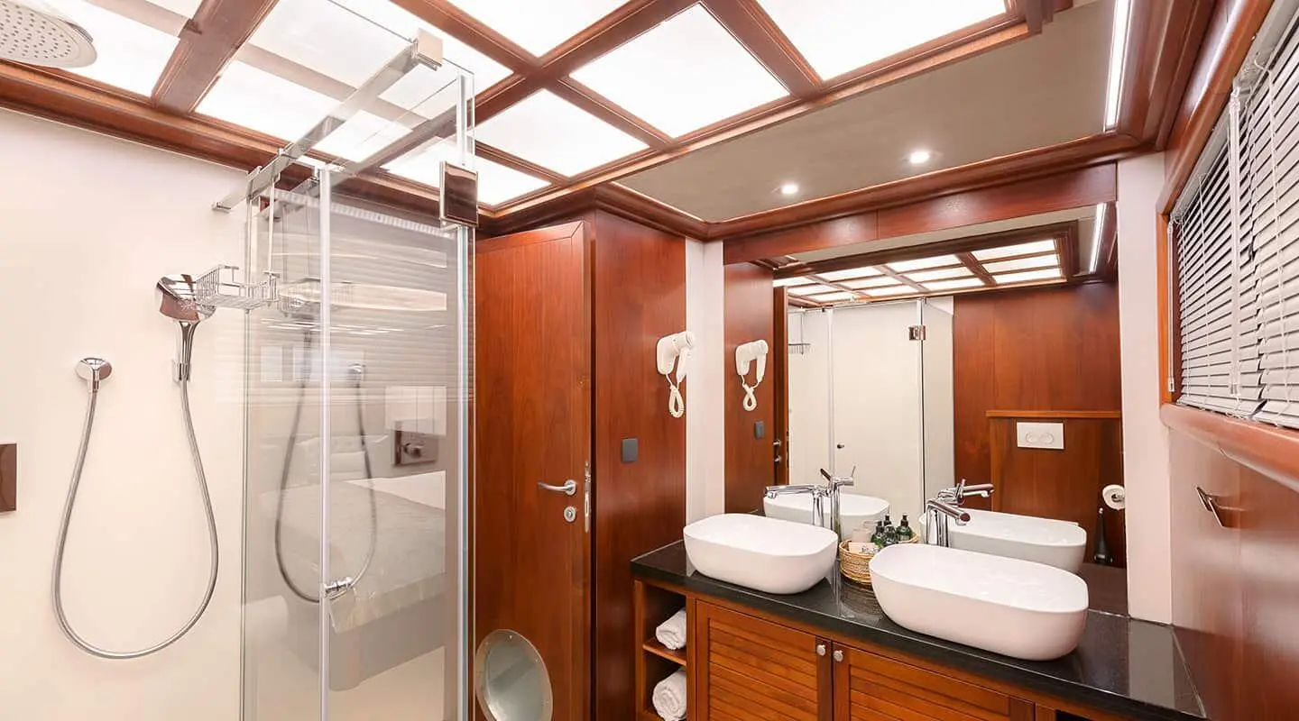 Interior aboard Lady Gita yacht: wooden cabinetry, double sinks, mirror, lighting