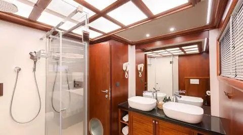 Interior aboard Lady Gita yacht: wooden cabinetry, double sinks, mirror, lighting