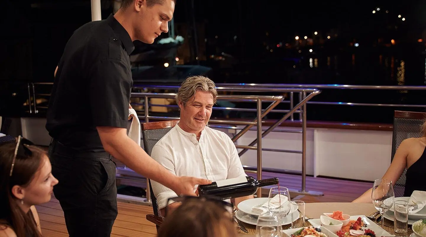 Dinner time on Queen Eleganza yacht with guests dining on deck at night