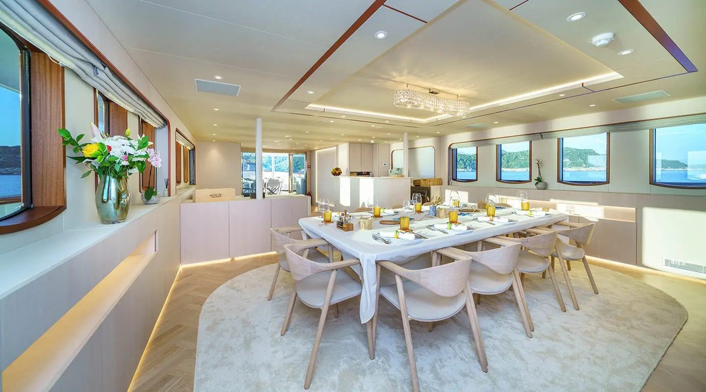 Maia yacht dining saloon: bright interior with round dining table and white chairs