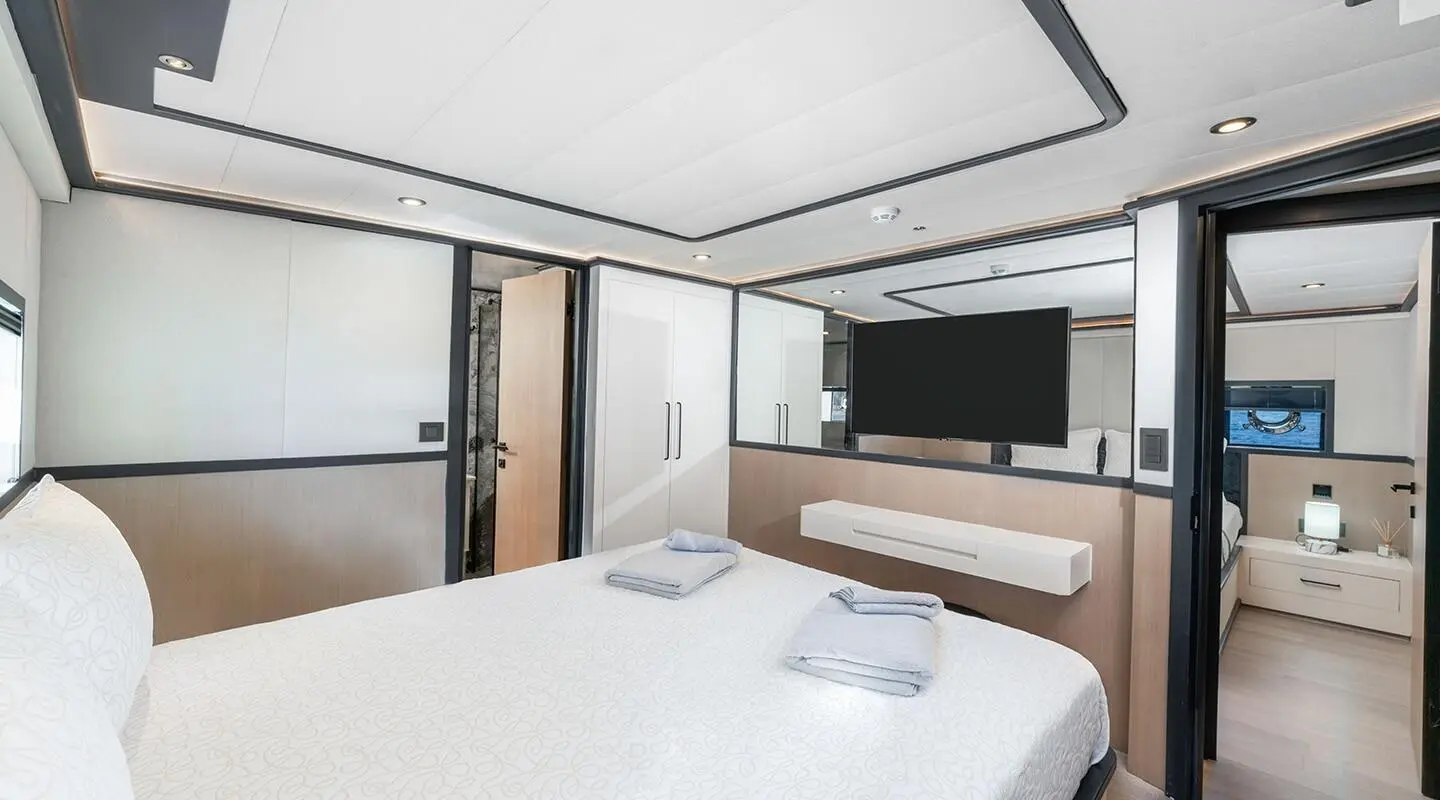 Calm Down yacht bedroom with bed, windows, and TV screen on deck interior