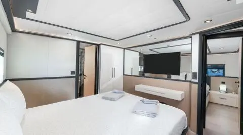 Calm Down yacht bedroom with bed, windows, and TV screen on deck interior